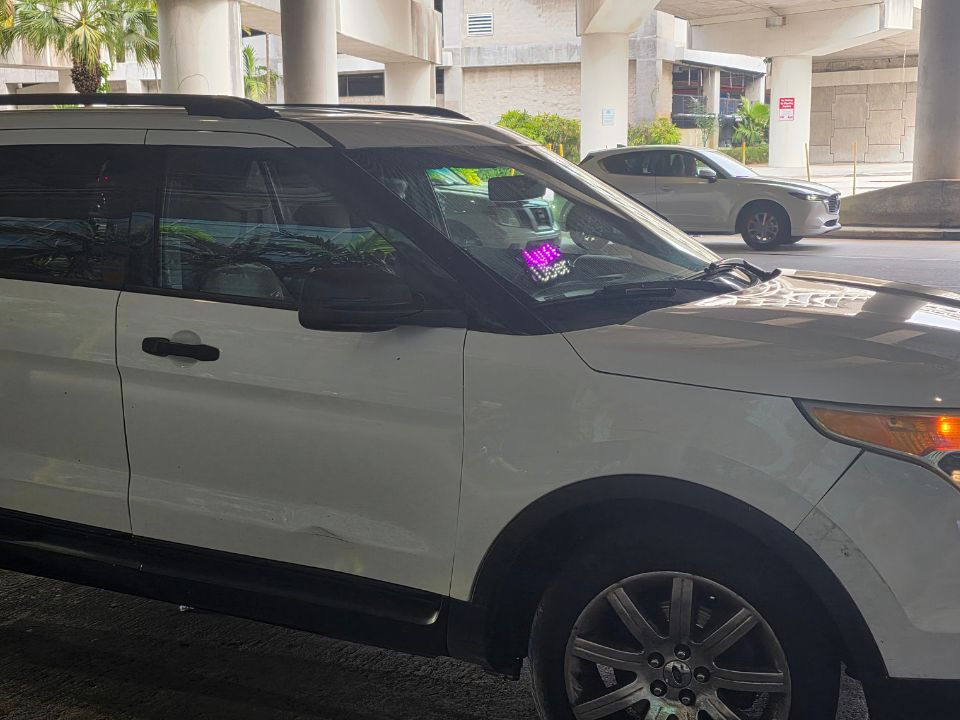 White rideshare SUV with trade dress decals at the Fort Lauderdale airport pickup area